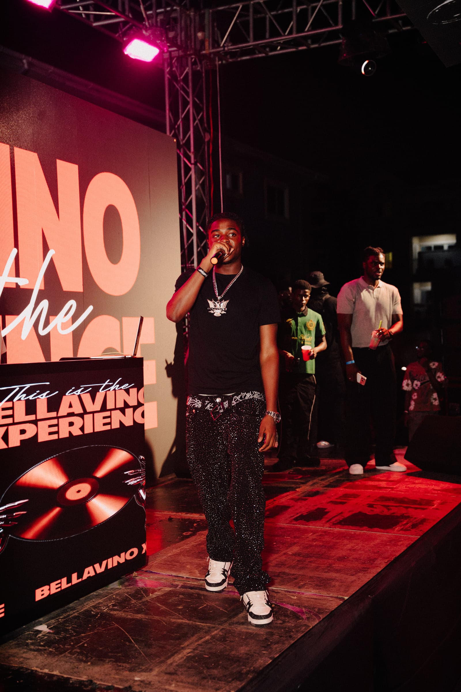 An artist performs at the front of the stage with the crew right behind
