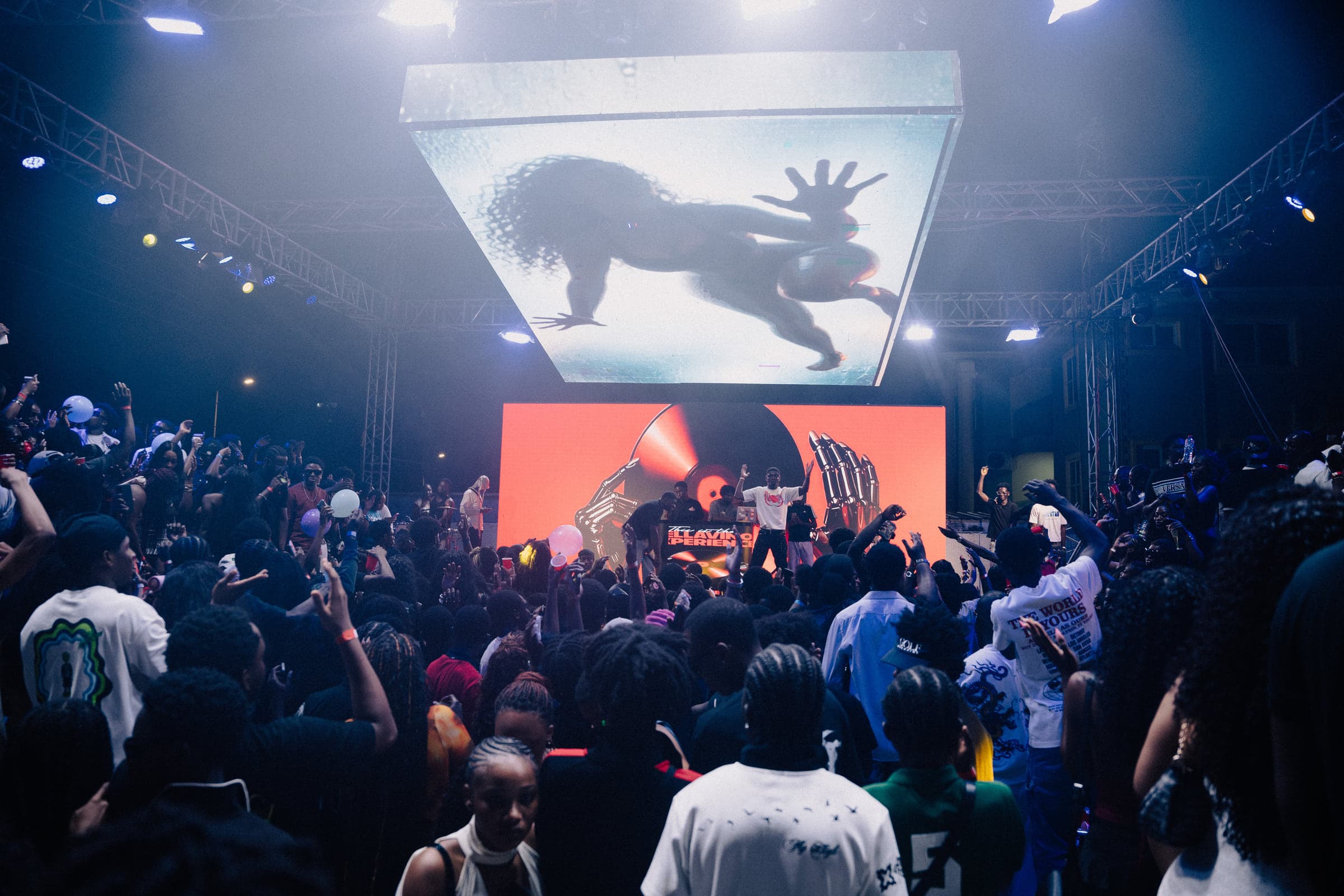 The crowd silhouetted against white stage lights and the big screen